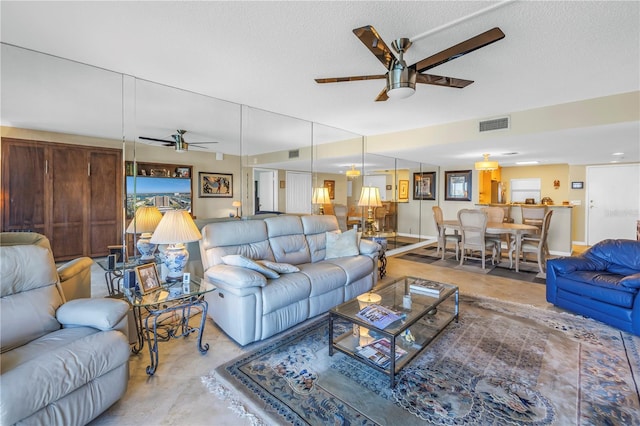 living area featuring a textured ceiling, visible vents, a healthy amount of sunlight, finished concrete flooring, and a ceiling fan