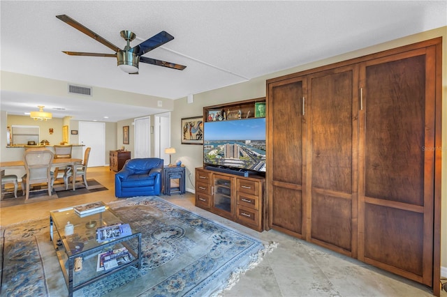 living area featuring a ceiling fan, visible vents, and a textured ceiling