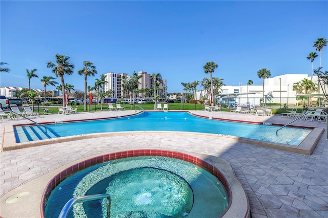 community pool with a patio area and a hot tub