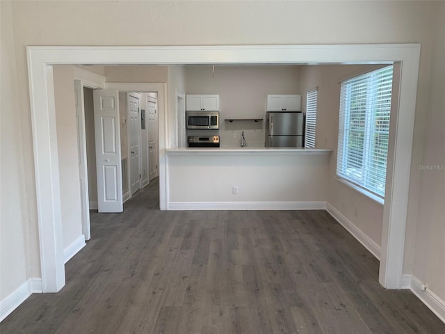 kitchen with stainless steel appliances, dark wood-style flooring, baseboards, white cabinets, and light countertops