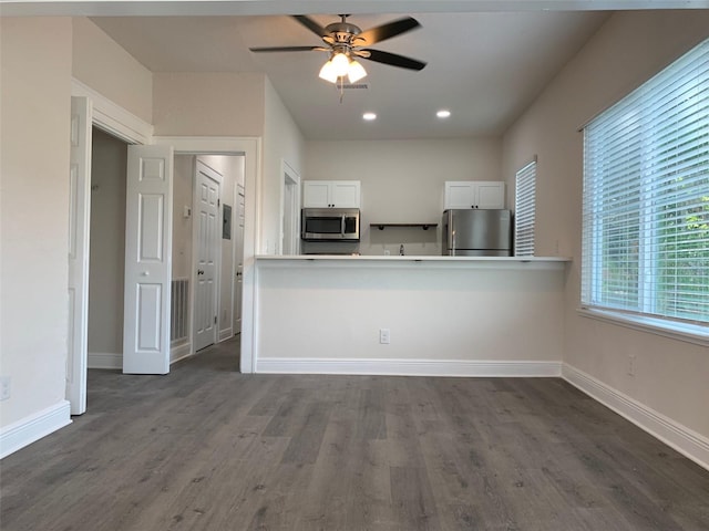 kitchen with stainless steel appliances, dark wood-type flooring, white cabinetry, ceiling fan, and baseboards