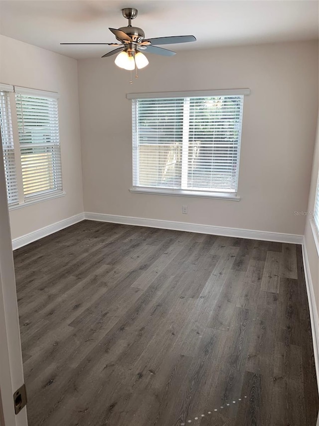 unfurnished room featuring a healthy amount of sunlight, dark wood finished floors, and baseboards