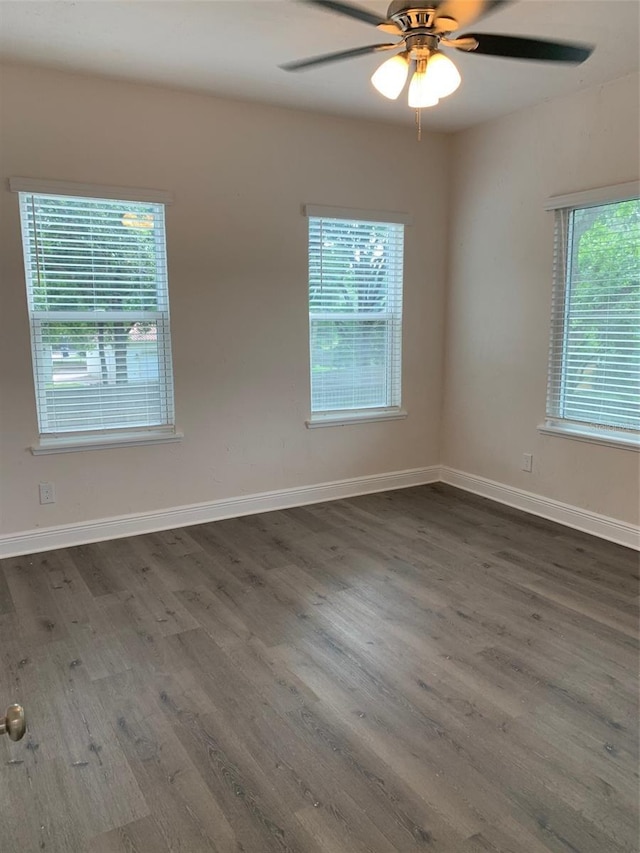 unfurnished room featuring dark wood-style flooring, a ceiling fan, and baseboards