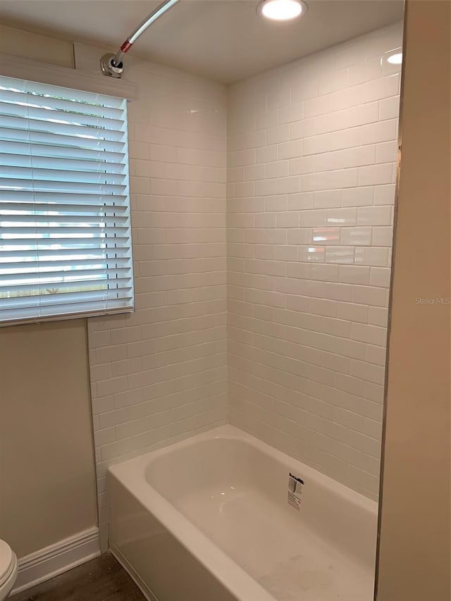 bathroom with shower / bath combination, baseboards, and toilet