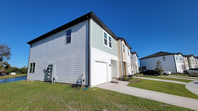 view of side of property with board and batten siding, a yard, driveway, and an attached garage