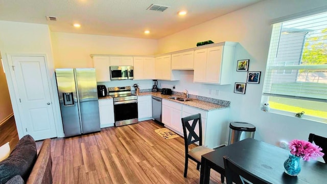 kitchen with visible vents, appliances with stainless steel finishes, light wood-style floors, white cabinets, and a sink