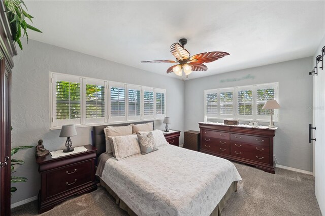 carpeted bedroom featuring a textured wall, baseboards, and ceiling fan