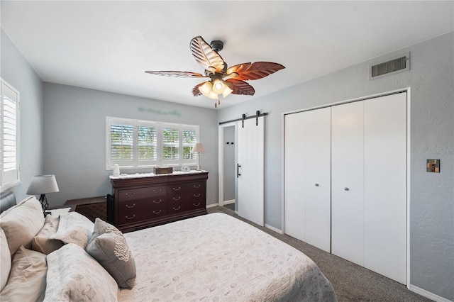 carpeted bedroom featuring a ceiling fan, a closet, visible vents, and a barn door