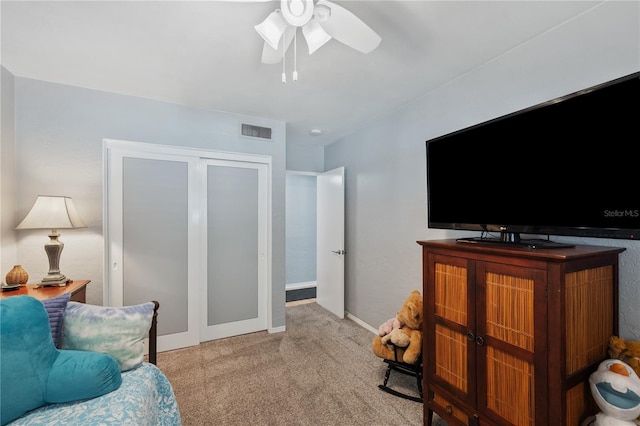 living area featuring baseboards, visible vents, ceiling fan, and carpet flooring