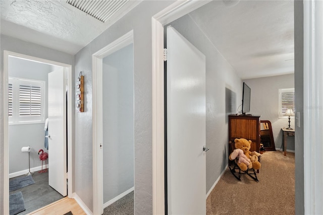 hall featuring carpet floors, visible vents, and baseboards