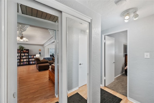 hall featuring a textured ceiling, a textured wall, and wood finished floors