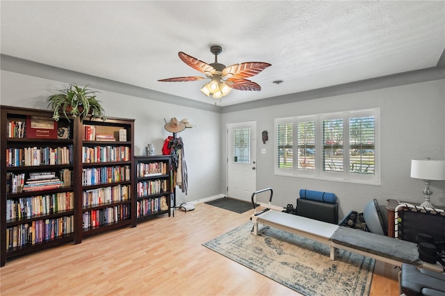 office featuring ceiling fan, a textured ceiling, baseboards, and wood finished floors