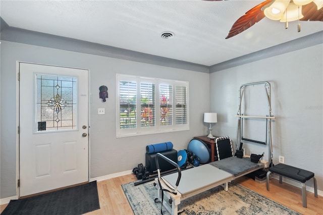 exercise room featuring light wood-type flooring, baseboards, visible vents, and a ceiling fan