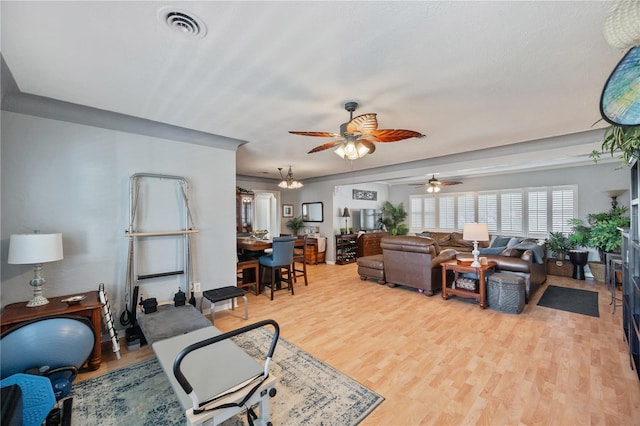 living area featuring light wood finished floors, visible vents, and a ceiling fan