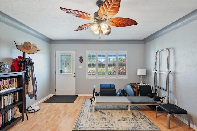 foyer entrance featuring ceiling fan, light wood-style flooring, baseboards, and a textured ceiling