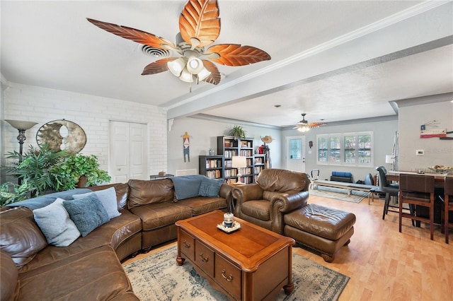 living area with ceiling fan, brick wall, crown molding, and light wood-style floors