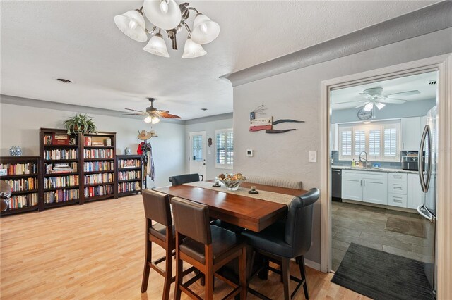 dining space featuring light wood-style floors, a ceiling fan, visible vents, and a wealth of natural light