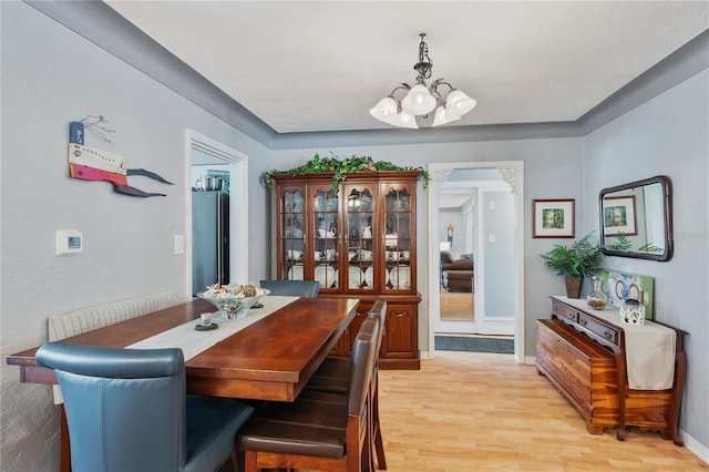 dining area featuring a chandelier, baseboards, and light wood finished floors