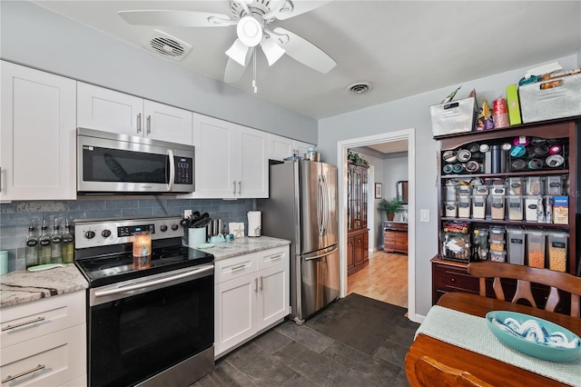 kitchen with tasteful backsplash, visible vents, white cabinets, light stone countertops, and stainless steel appliances