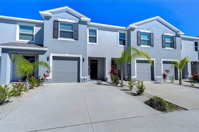 multi unit property with stucco siding, a garage, and driveway