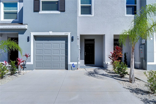 doorway to property with stucco siding, a garage, and concrete driveway