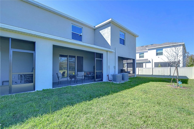 back of house featuring fence, a sunroom, stucco siding, central air condition unit, and a lawn