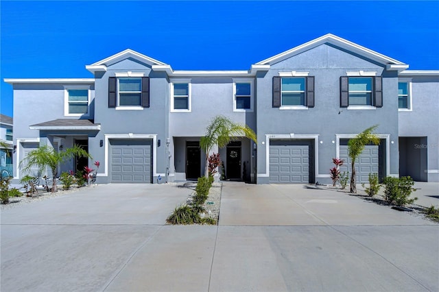 multi unit property featuring an attached garage, driveway, and stucco siding