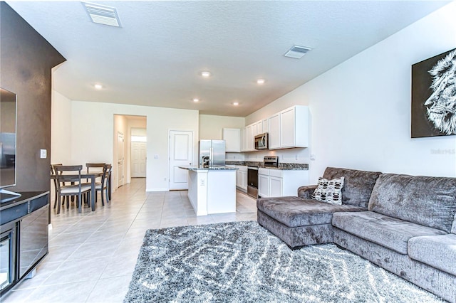 living room featuring light tile patterned floors, recessed lighting, visible vents, and a textured ceiling