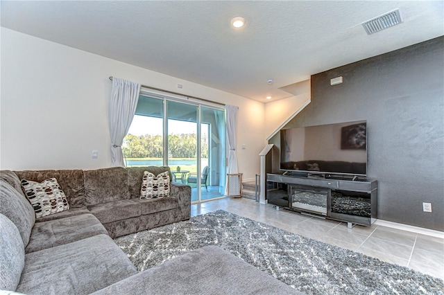 tiled living area with visible vents and a textured ceiling