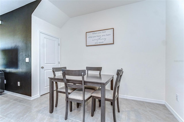 dining room featuring light tile patterned flooring, baseboards, and vaulted ceiling