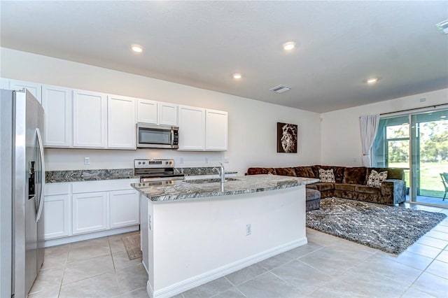 kitchen with visible vents, open floor plan, dark stone countertops, appliances with stainless steel finishes, and white cabinetry