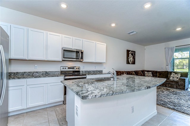 kitchen with dark stone countertops, light tile patterned floors, visible vents, a sink, and appliances with stainless steel finishes