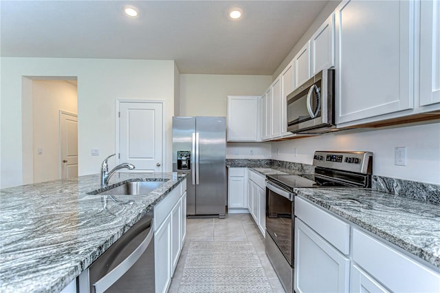 kitchen featuring a sink, white cabinets, light stone counters, and stainless steel appliances