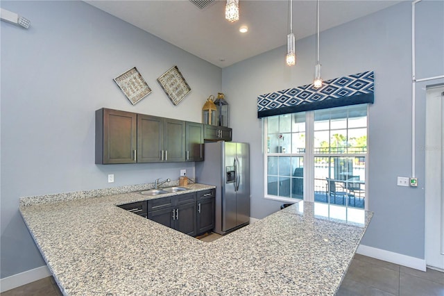 kitchen featuring stainless steel refrigerator with ice dispenser, a sink, decorative light fixtures, baseboards, and light stone countertops