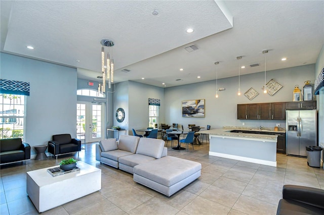 living area with light tile patterned floors, visible vents, a textured ceiling, and french doors