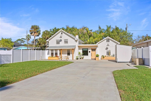 modern farmhouse with a front yard, covered porch, and fence