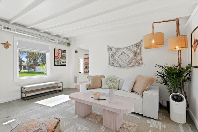 sitting room featuring baseboards, visible vents, arched walkways, and beam ceiling