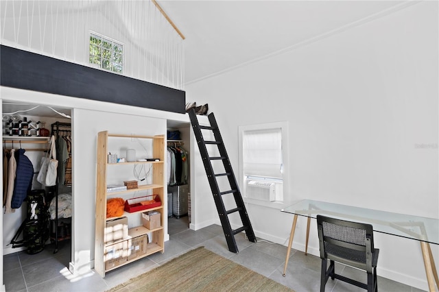 tiled bedroom with cooling unit, a walk in closet, and baseboards