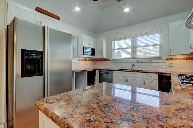 kitchen with a sink, light stone counters, white cabinetry, and stainless steel appliances