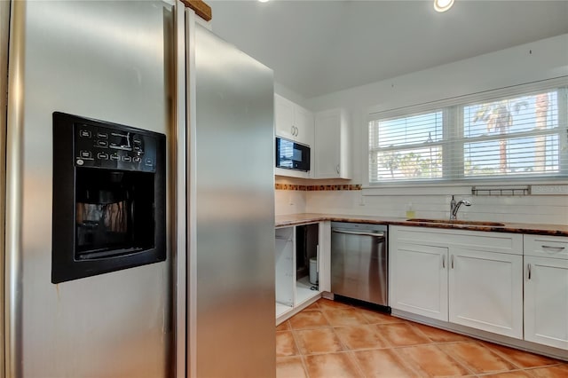 kitchen with white cabinets, light tile patterned floors, appliances with stainless steel finishes, and a sink