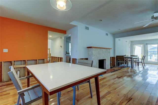 kitchen featuring visible vents, a ceiling fan, light wood-style flooring, and a fireplace