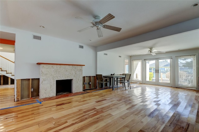 unfurnished living room with wood finished floors, visible vents, a high end fireplace, and ceiling fan