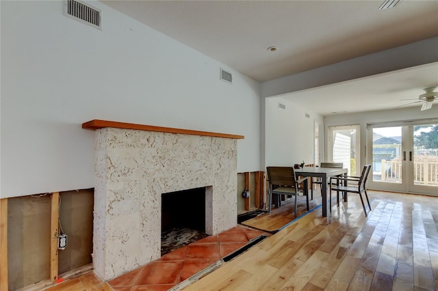 living room featuring a premium fireplace, visible vents, french doors, and wood finished floors
