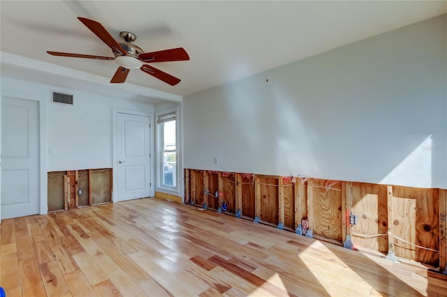 empty room featuring visible vents, a ceiling fan, and wood finished floors