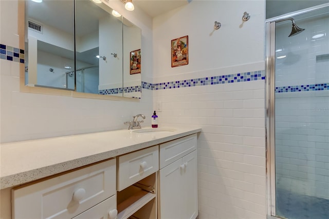 full bath with vanity, tile walls, visible vents, and a shower stall