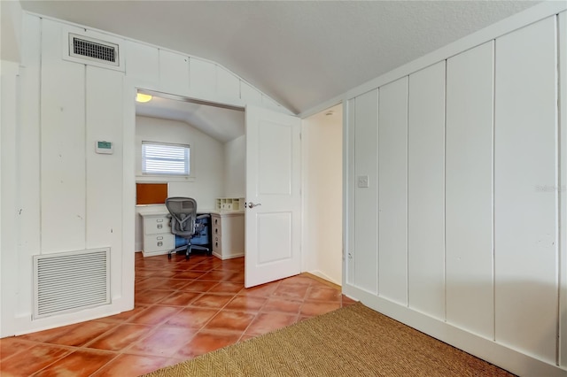 interior space featuring light tile patterned floors, visible vents, and vaulted ceiling
