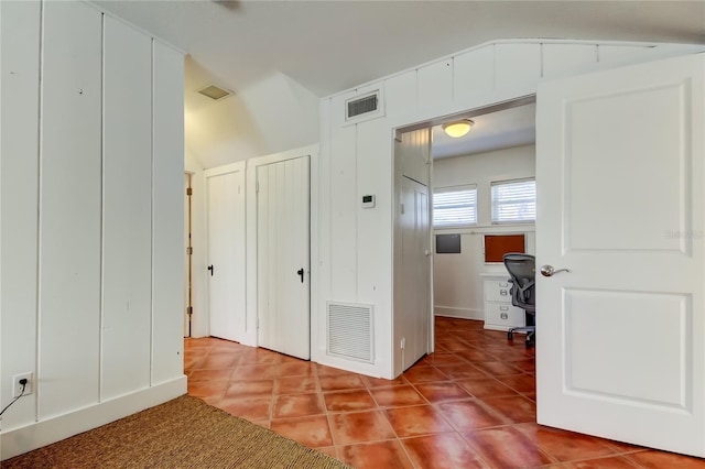 corridor with tile patterned flooring, visible vents, and vaulted ceiling