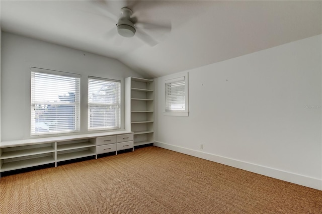 unfurnished bedroom with baseboards, lofted ceiling, light colored carpet, and ceiling fan