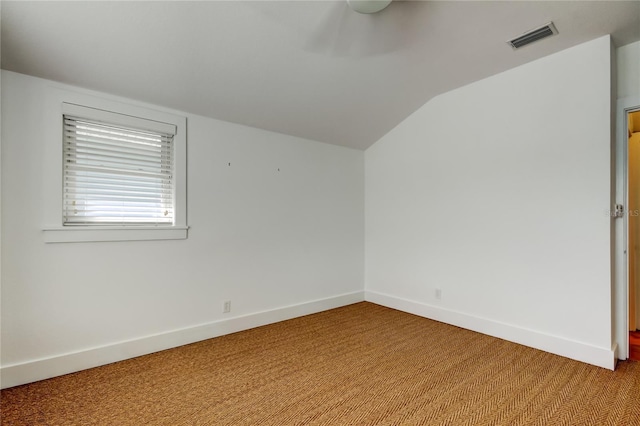 spare room with visible vents, baseboards, ceiling fan, light colored carpet, and lofted ceiling