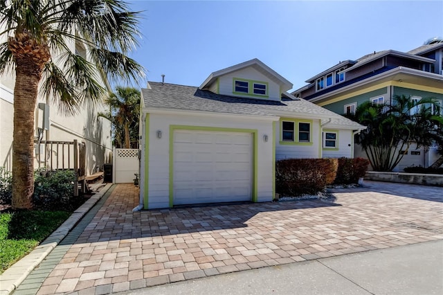 view of front of house with roof with shingles, a garage, and fence